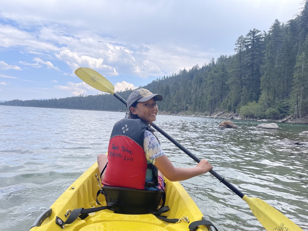 Malia (me) kayaking at Lake Tahoe, turning back to smile at the camera